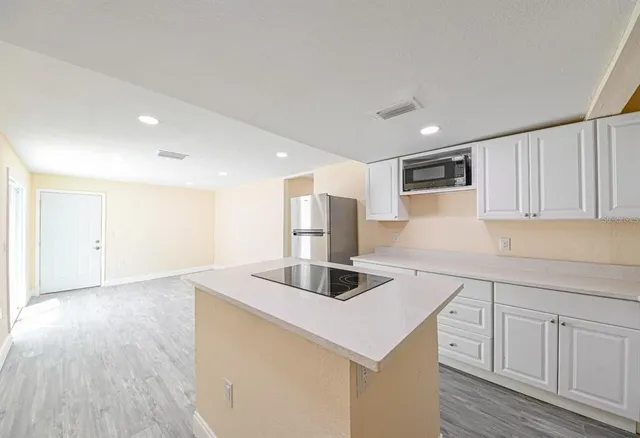 a kitchen with kitchen island a sink appliances and cabinets