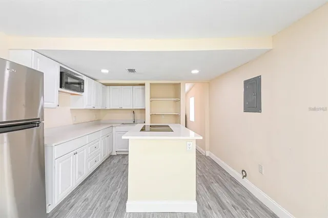 a kitchen with a sink a refrigerator and white cabinets