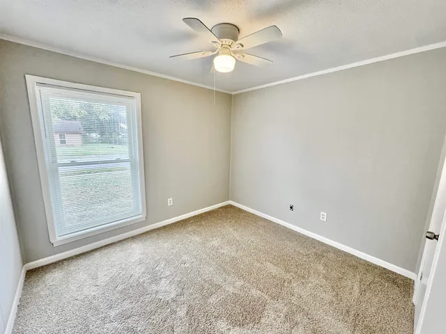 an empty room with a window and a fan