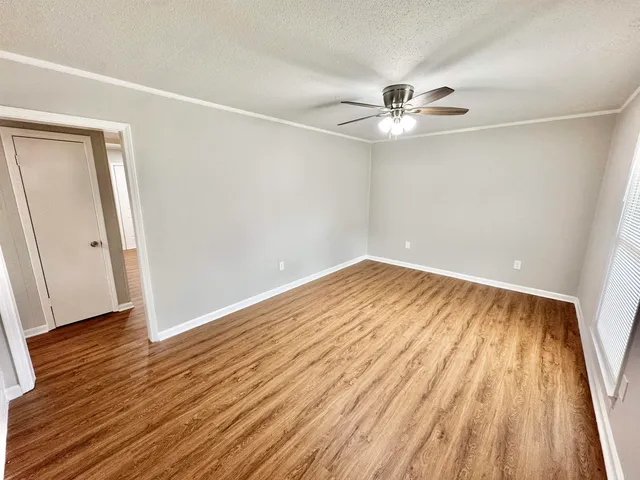 an empty room with wooden floor and a ceiling fan