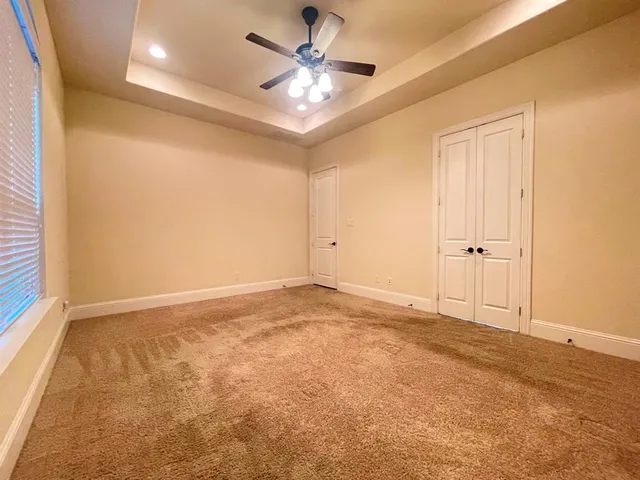 an empty room with a ceiling fan and a window