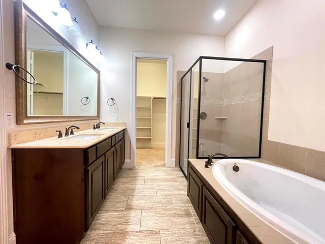 a spacious bathroom with a tub sink shower and mirror