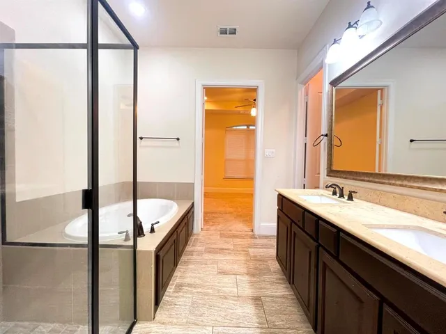 a bathroom with a double vanity sink and mirror with bathtub