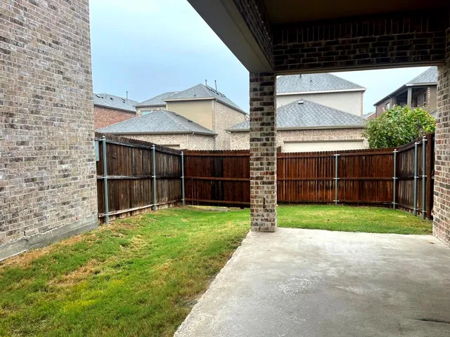 a view of a backyard with wooden fence and a large tree