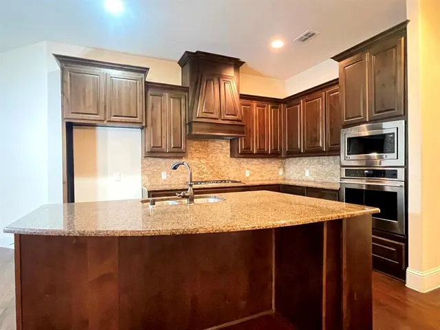 a kitchen with kitchen island granite countertop a stove refrigerator and cabinets