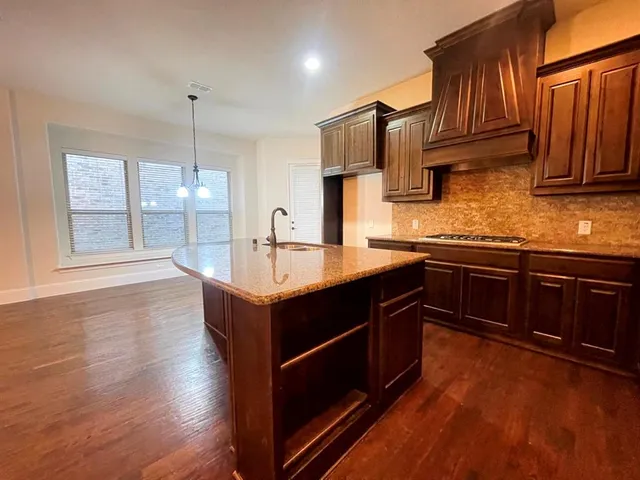 a kitchen with stainless steel appliances granite countertop wooden cabinets a sink dishwasher a stove and a refrigerator