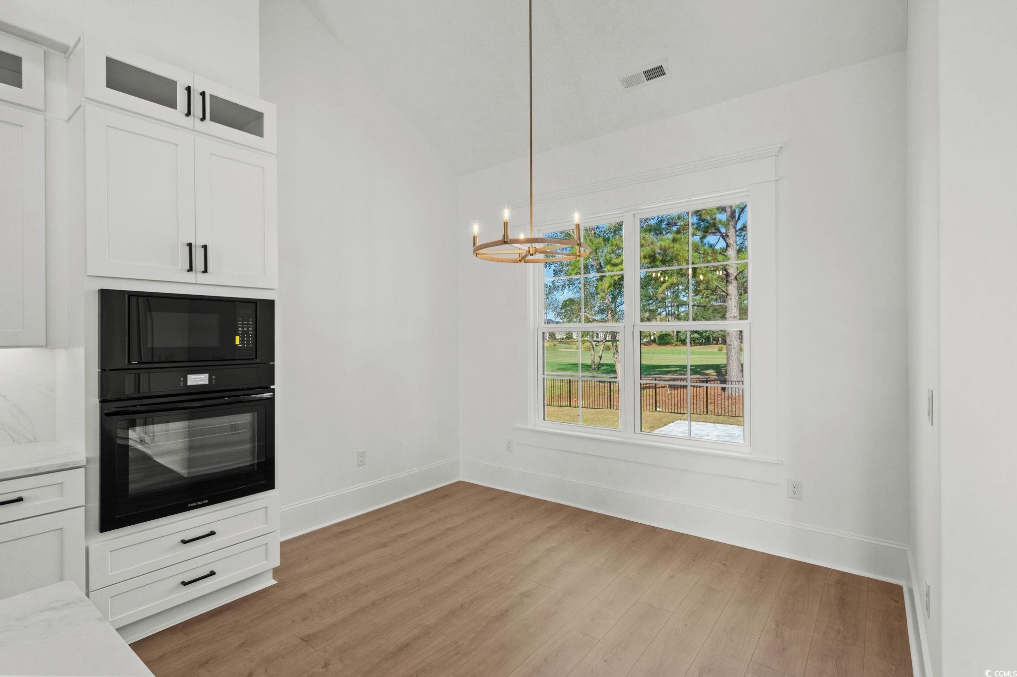 9282 Checkerberry Square Calabash, NC 28467 - Photo 11 of 40 Kitchen featuring white cabinets, black appliances, lofted ceiling, light wood-style flooring, and decorative light fixtures