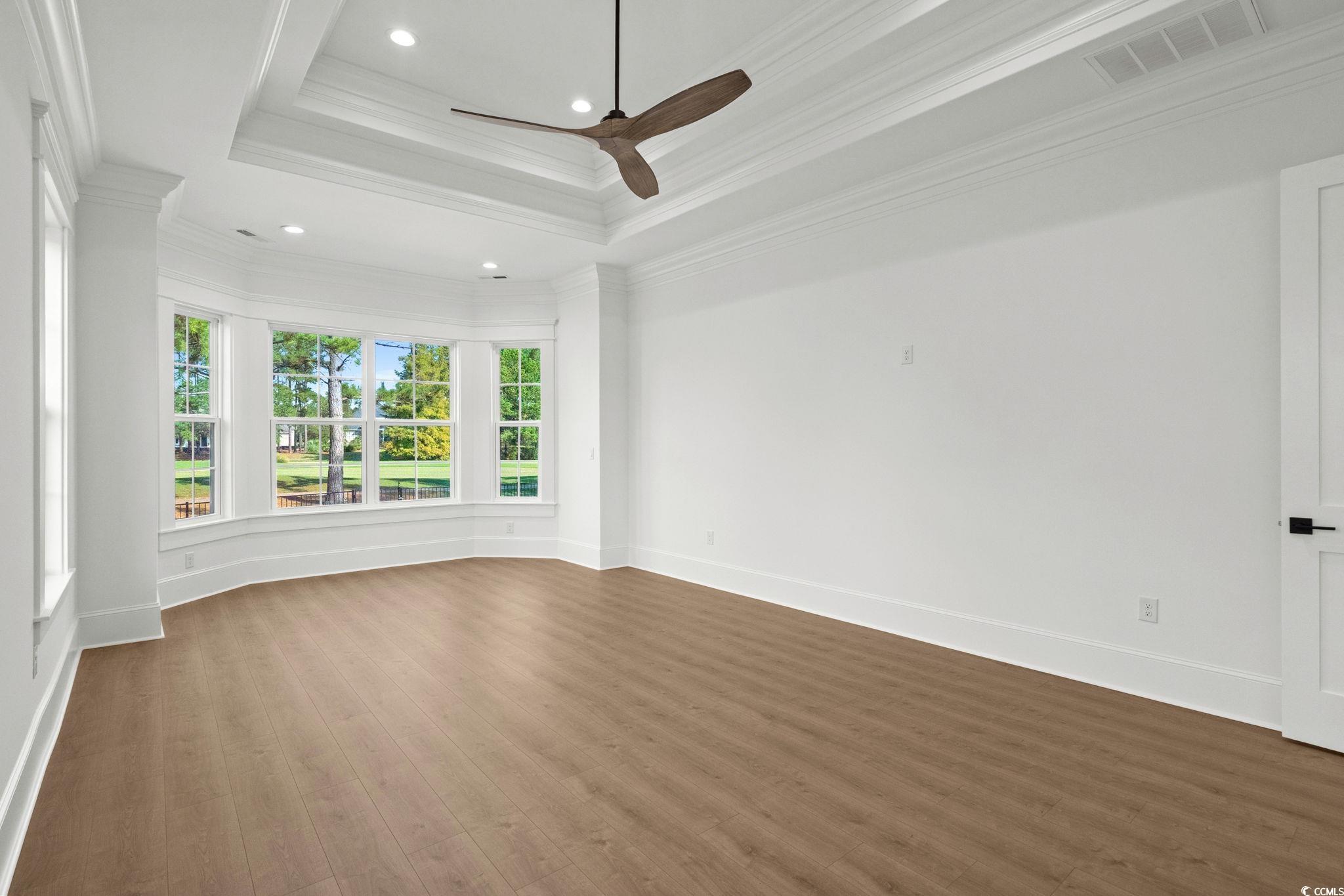 9282 Checkerberry Square Calabash, NC 28467 - Photo 14 of 40 Unfurnished room with a raised ceiling, ornamental molding, wood finished floors, a ceiling fan, and recessed lighting
