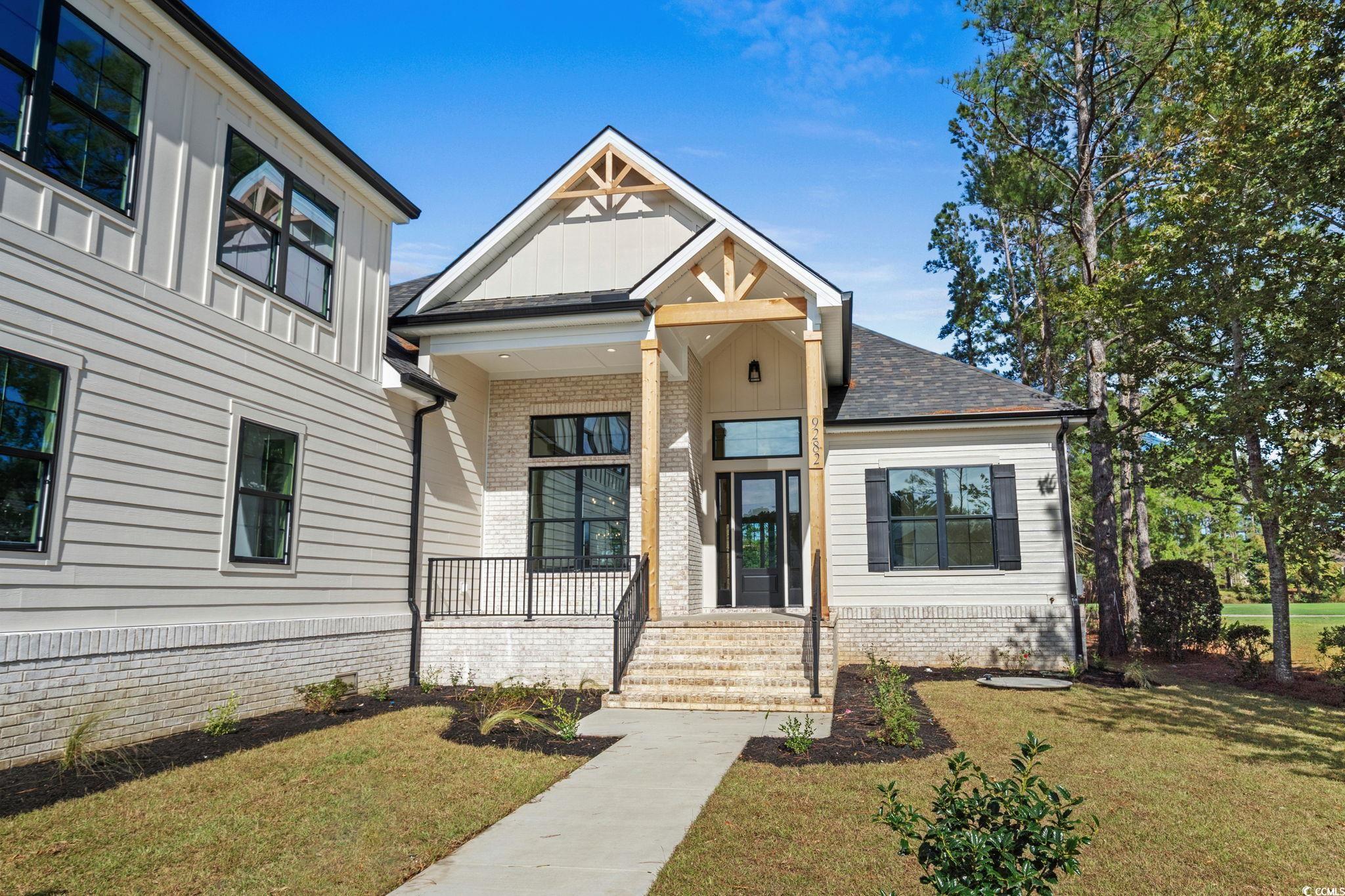 9282 Checkerberry Square Calabash, NC 28467 - Photo 3 of 40 Modern farmhouse with a front lawn, a porch, brick siding, and roof with shingles
