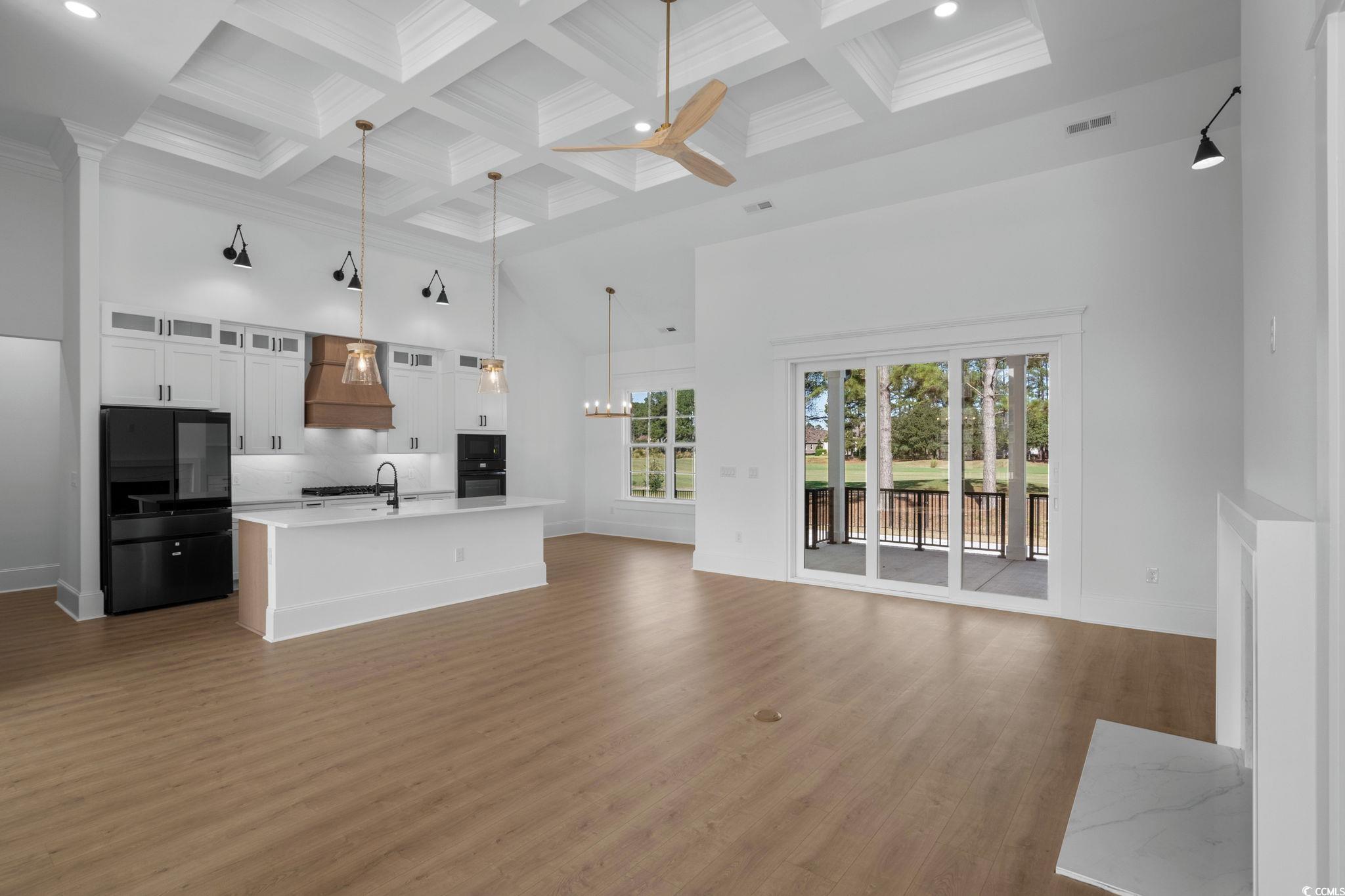9282 Checkerberry Square Calabash, NC 28467 - Photo 39 of 40 Kitchen featuring a towering ceiling, open floor plan, glass insert cabinets, freestanding refrigerator, and beam ceiling