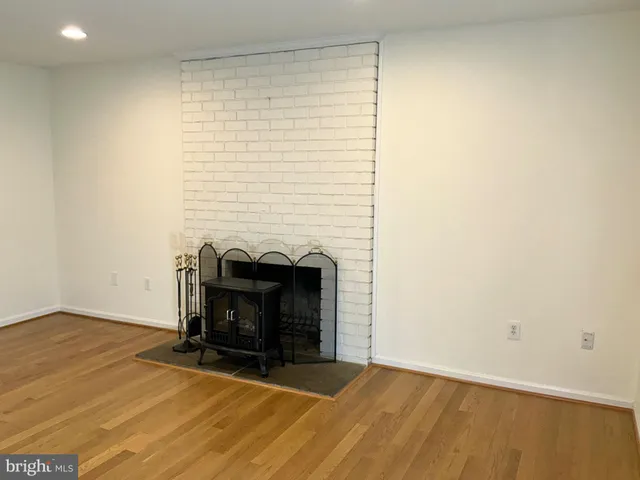 a view of an empty room with wooden floor and a fireplace