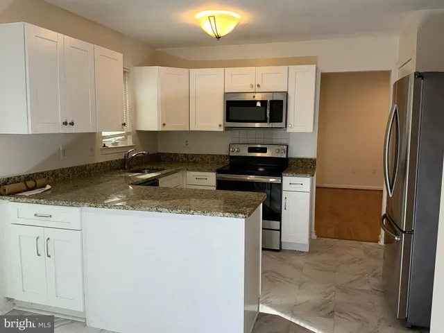 a kitchen with stainless steel appliances granite countertop a refrigerator a stove a sink and white cabinets