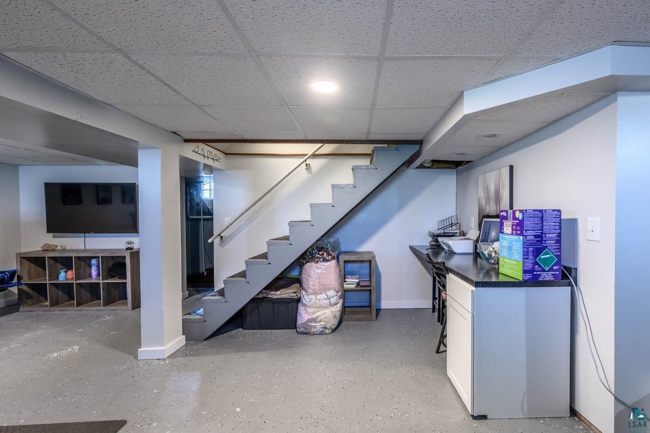 2581 O'Rourke Road Hibbing, MN 55746 - Photo 26 of 61 Finished lower level featuring a drop ceiling with recessed lighting, painted staircase with metal handrail, light gray epoxy flooring, and a built-in countertop with cabinetry