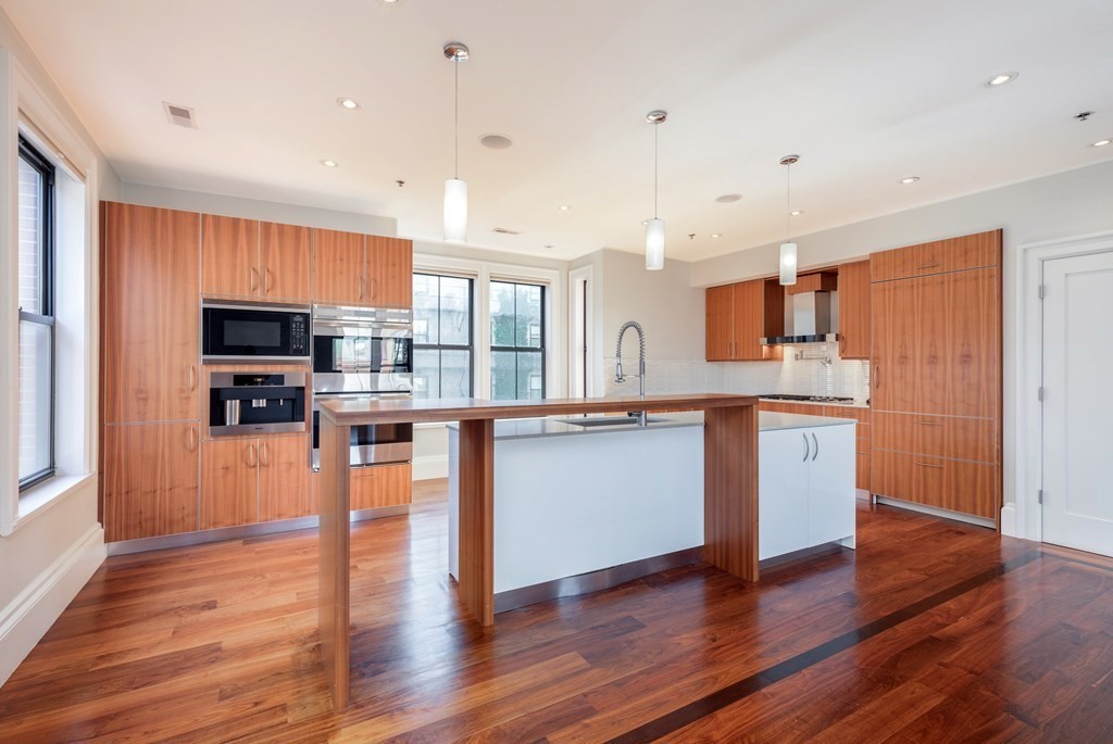 a kitchen with stainless steel appliances granite countertop a refrigerator a stove top oven a sink dishwasher and wooden floor