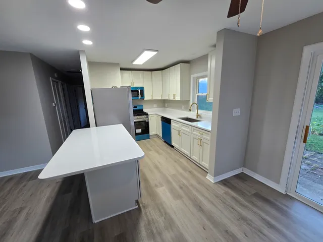 a large kitchen with sink a refrigerator and wooden floor