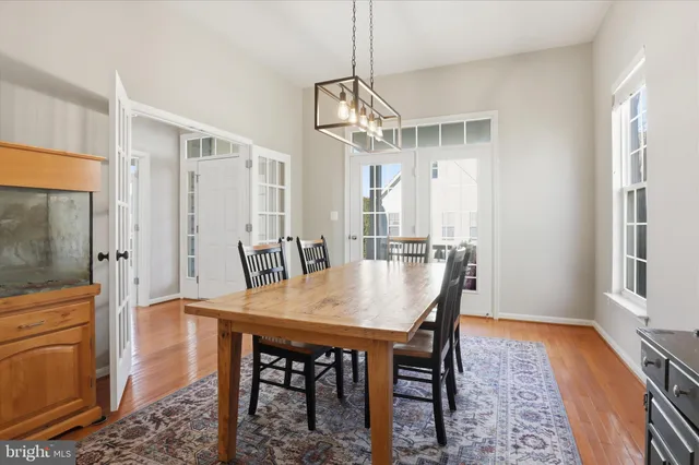 a dining room with wooden floor a chandelier a wooden table and chairs