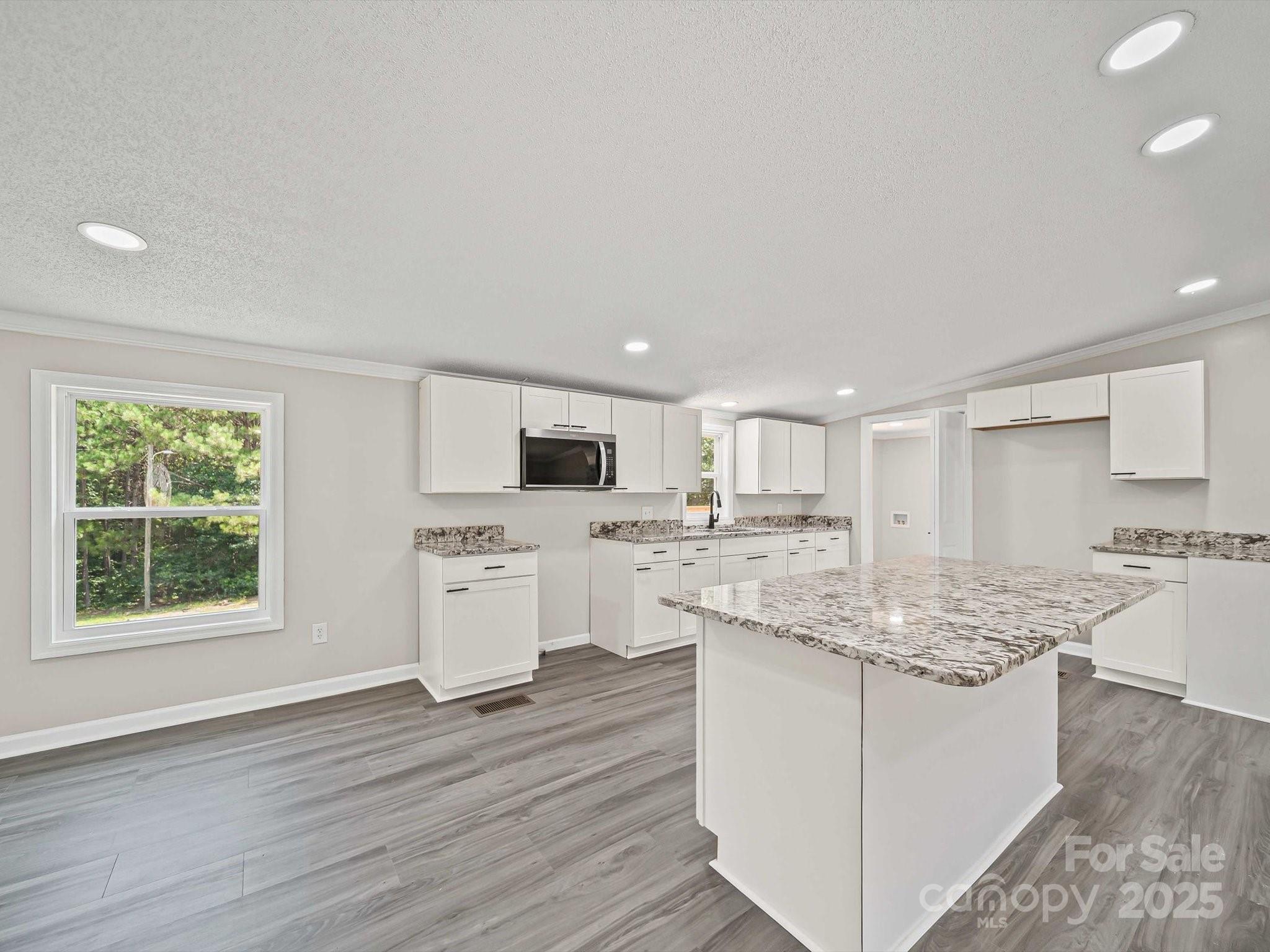 147 Xienghone Road Mount Gilead, NC 27306 - Photo 11 of 22 a kitchen with kitchen island granite countertop white cabinets and stainless steel appliances