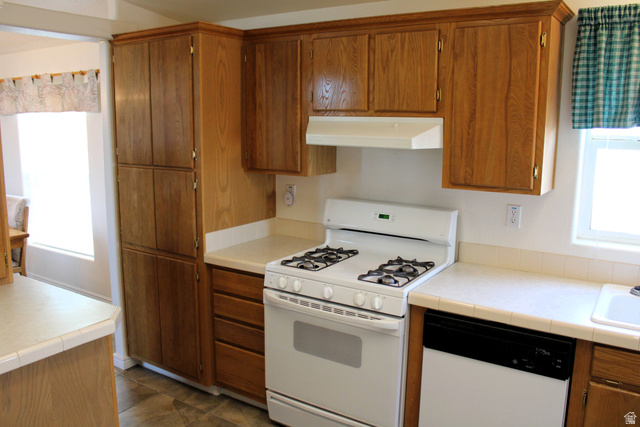 22580 Spring Creek Drive, Unit B61 Fairview, UT 84629 - Photo 12 of 39 Kitchen featuring wood-finish cabinetry, white countertops, a white gas range, and a white dishwasher