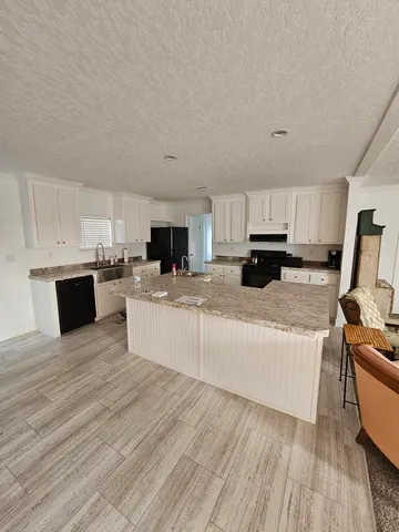 a large white kitchen with cabinets a sink a stove and a refrigerator