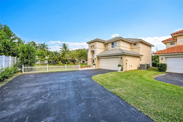 a view of a house with a big yard plants and large trees