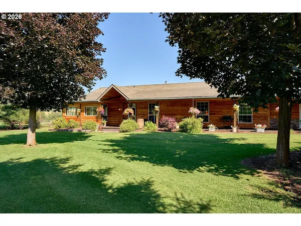 a view of a house with a big yard and large tree