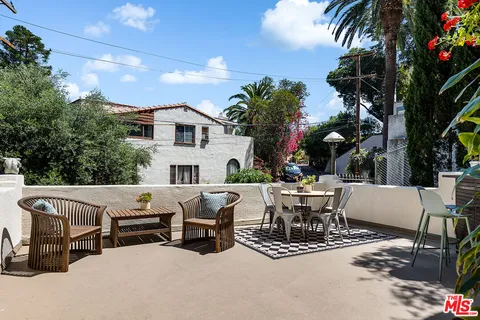a view of a patio with couches table and chairs and potted plants