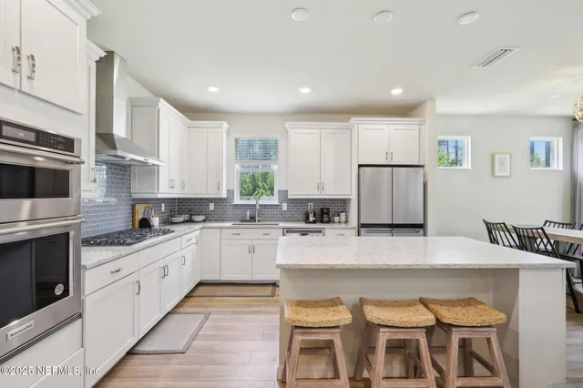 a large kitchen with stainless steel appliances granite countertop a stove a sink a dining table and chairs