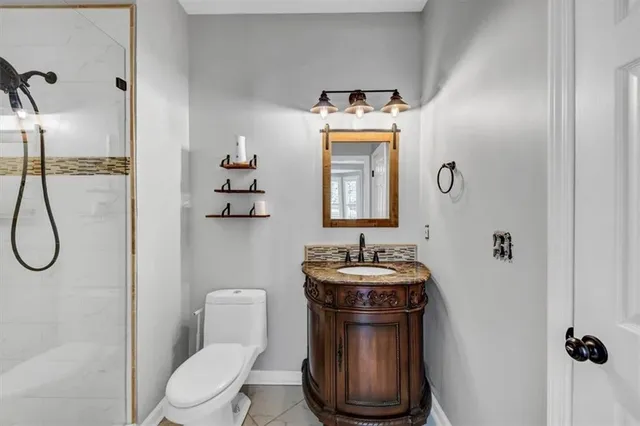 a bathroom with a granite countertop toilet a sink and a mirror