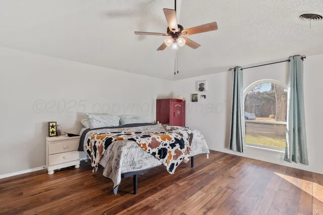 a bedroom with a bed and a large mirror with a wooden floor