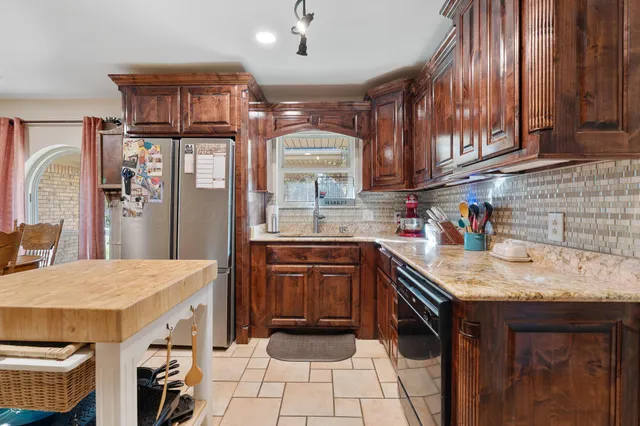 a kitchen with stainless steel appliances granite countertop a refrigerator a stove and a sink with cabinets