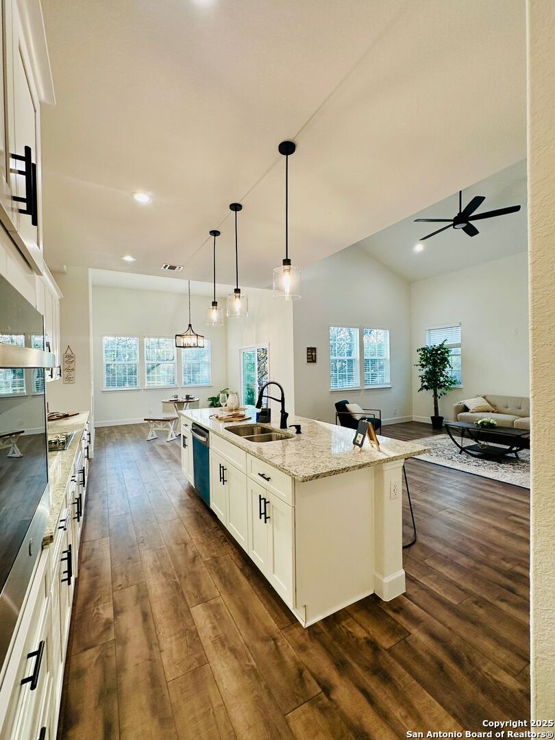 1064 Overbrook Lane Spring Branch, TX 78070 - Photo 14 of 34 a large white kitchen with kitchen island a stove a sink a refrigerator and white cabinets with wooden floor