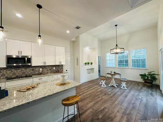 a large kitchen with granite countertop a stove a sink a window and chairs