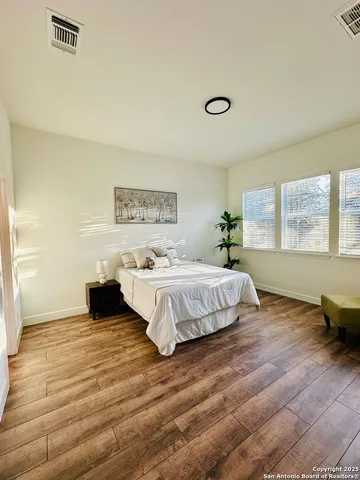 a spacious bedroom with a bed and wooden floor
