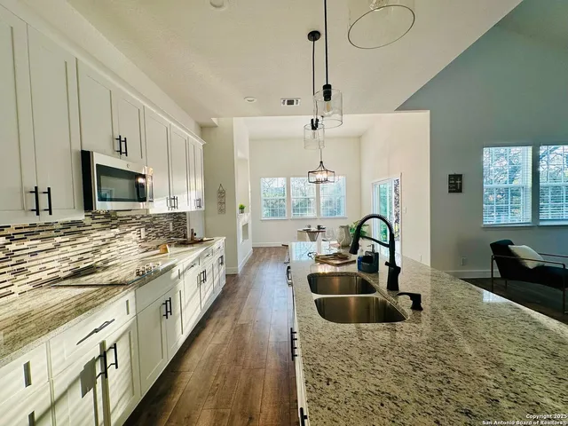 a large kitchen with granite countertop a sink a counter space appliances and cabinets
