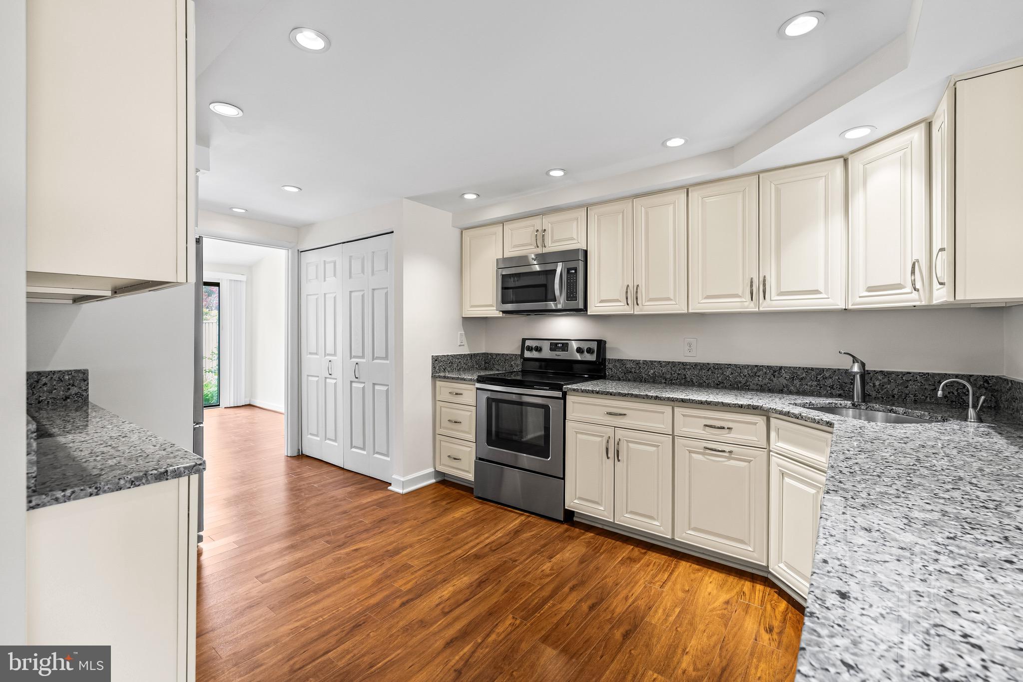 11 Tanner Court, Unit G Baltimore, MD 21208 - Photo 11 of 38 a kitchen with granite countertop a stove top oven a sink dishwasher and a refrigerator with wooden floor