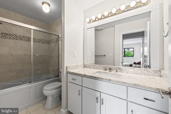 a bathroom with a granite countertop sink a toilet and shower