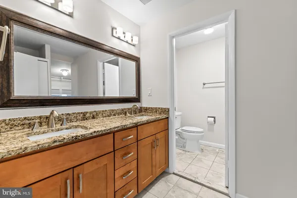 a bathroom with a granite countertop toilet sink and a mirror