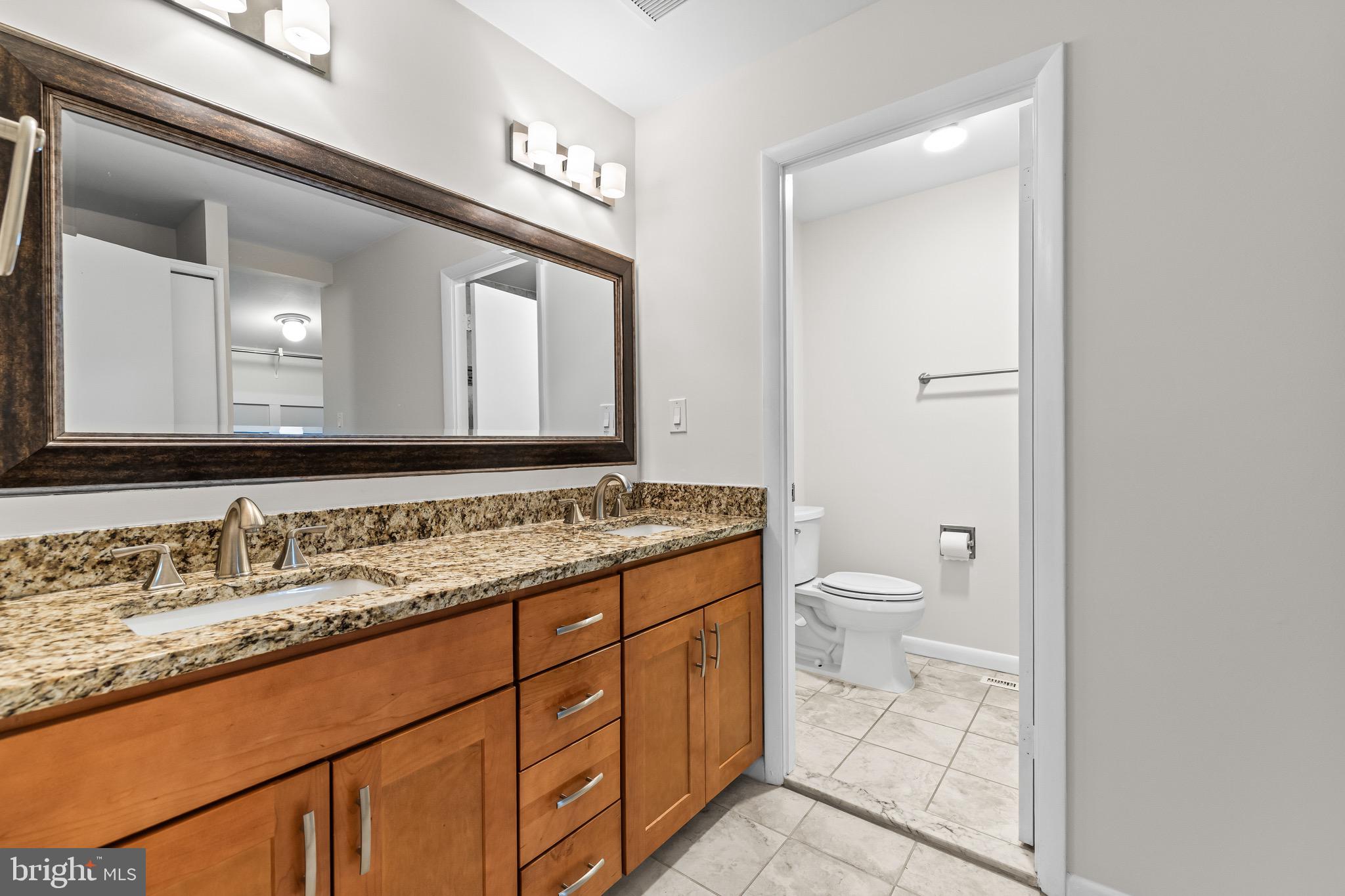 11 Tanner Court, Unit G Baltimore, MD 21208 - Photo 31 of 38 a bathroom with a granite countertop toilet sink and a mirror