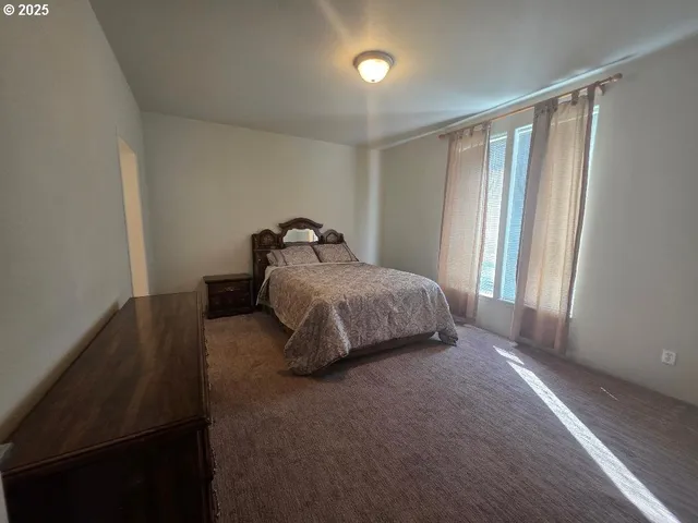 an empty room with wooden floor and windows with curtains view
