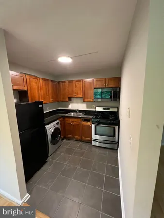 a kitchen with granite countertop a refrigerator and a stove top oven