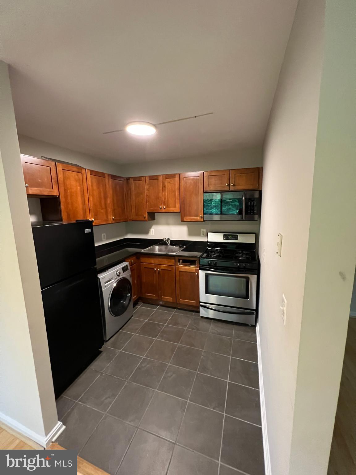 3111 Naylor Road Southeast, Unit 301 Washington, DC 20020 - Photo 5 of 11 a kitchen with granite countertop a refrigerator and a stove top oven