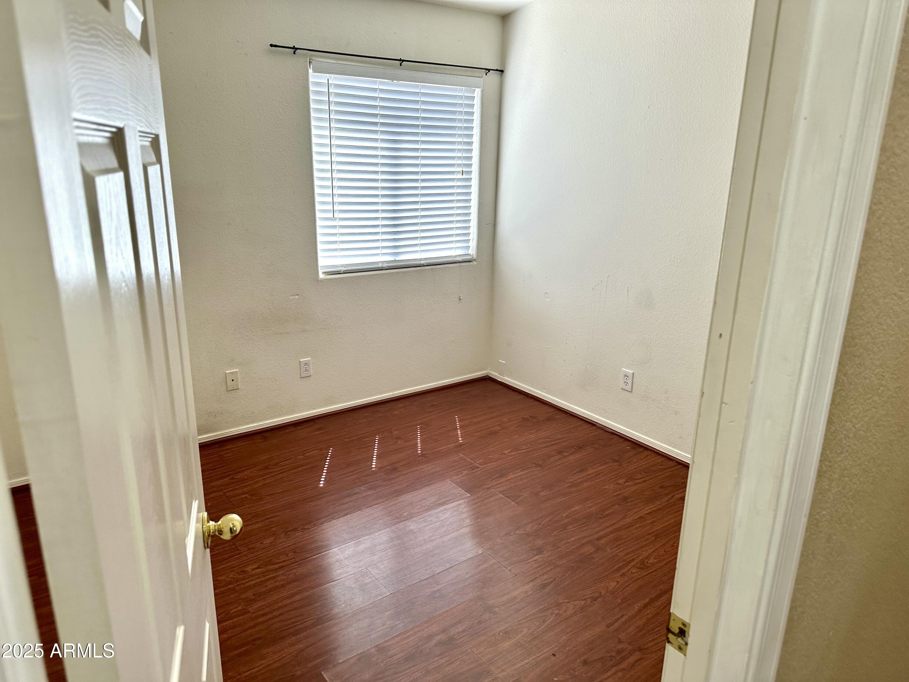 592 East 9th Avenue Apache Junction, AZ 85119 - Photo 12 of 19 an empty room with wooden floor and a window
