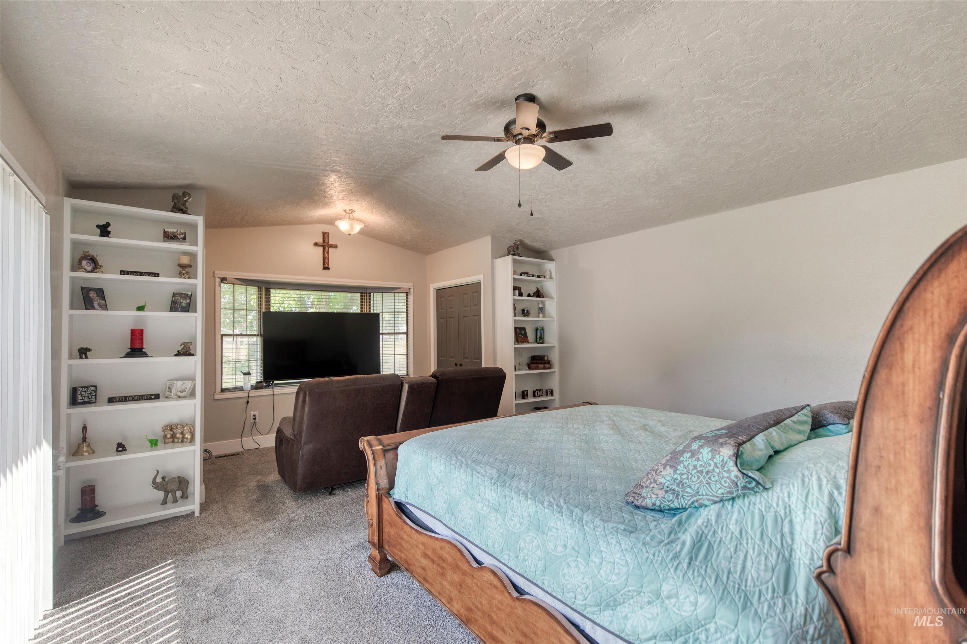 20803 Friends Road Greenleaf, ID 83626 - Photo 11 of 39 Carpeted room featuring a bay window, two built-in shelving units, a ceiling fan, and a vaulted ceiling