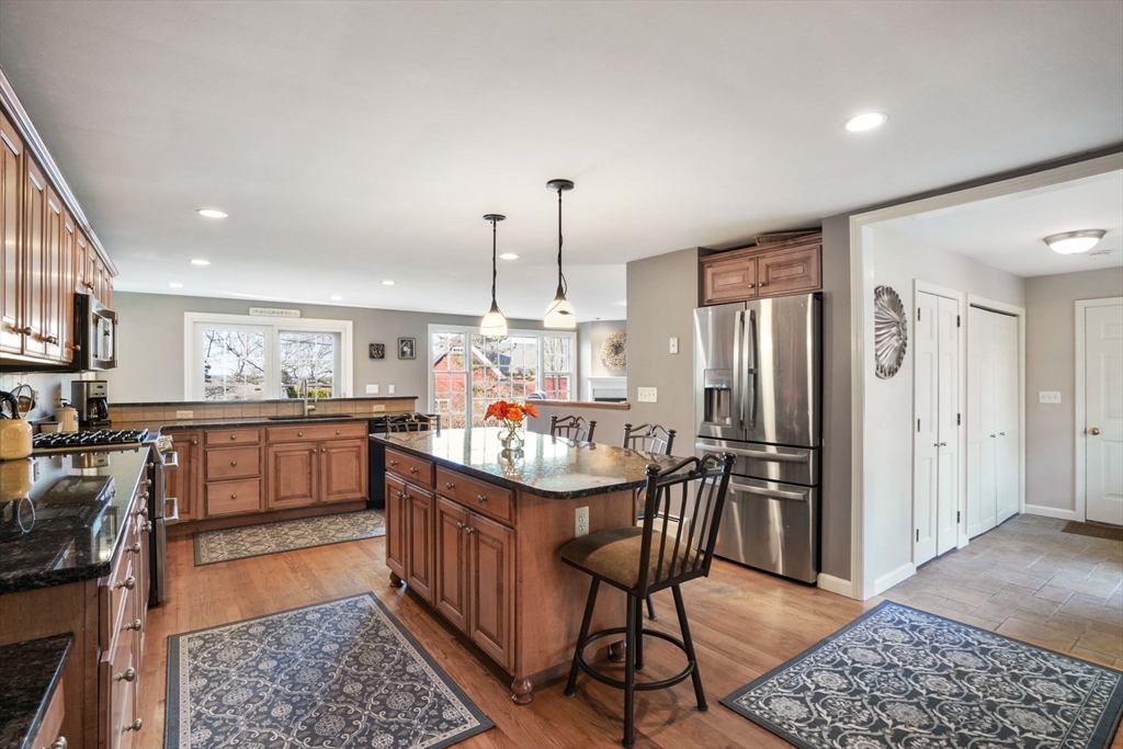 4 Longview Road Chelmsford, MA 01824 - Photo 5 of 36 a kitchen with stainless steel appliances granite countertop a refrigerator a stove a sink a dining table and chairs with wooden floor