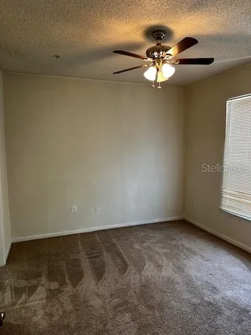 a view of a chandelier fan and window in an empty room