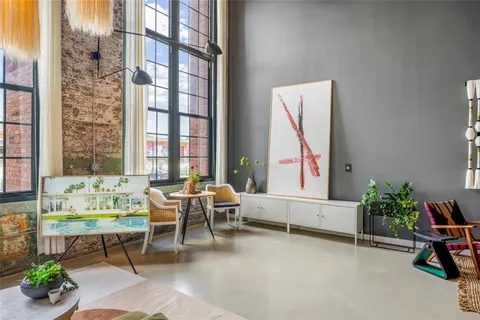 a hallway with painting on the wall and a potted plant