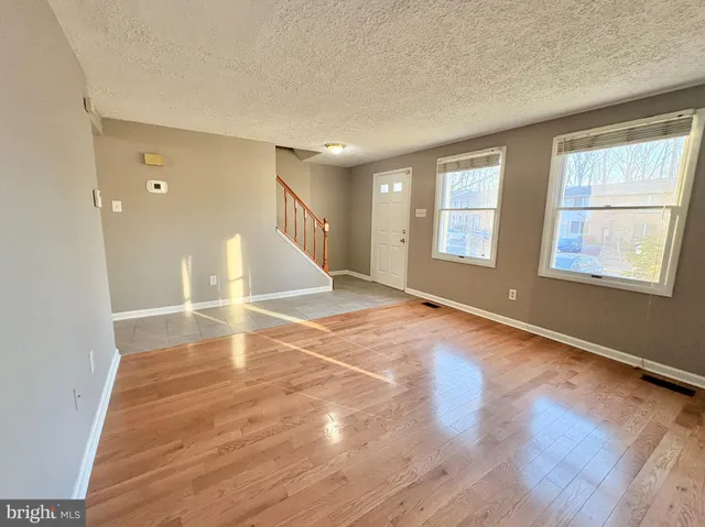 an empty room with wooden floor and windows