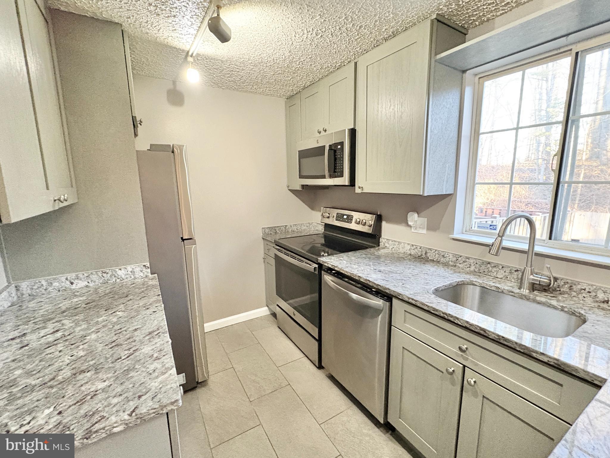 8263 Burning Forest Court Springfield, VA 22153 - Photo 10 of 43 a kitchen with stainless steel appliances granite countertop a sink and a refrigerator
