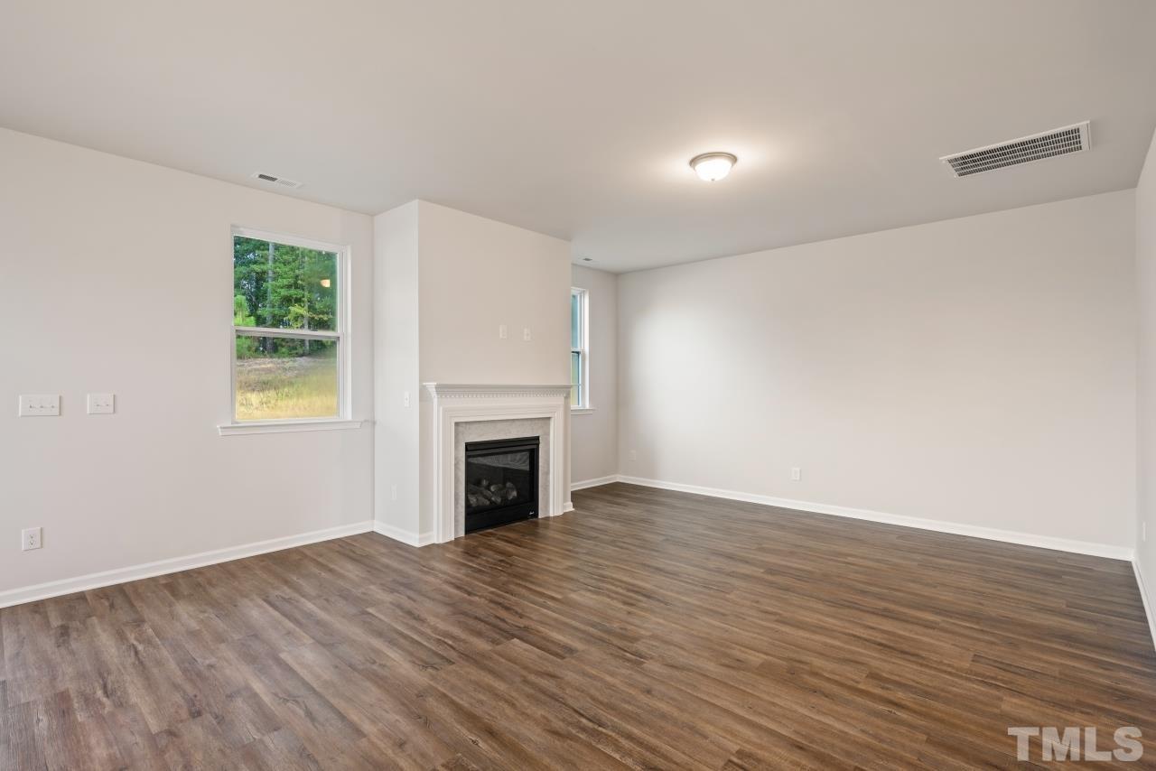 129 Scoville Road Garner, NC 27529 - Photo 12 of 25 a view of empty room with wooden floor and fireplace