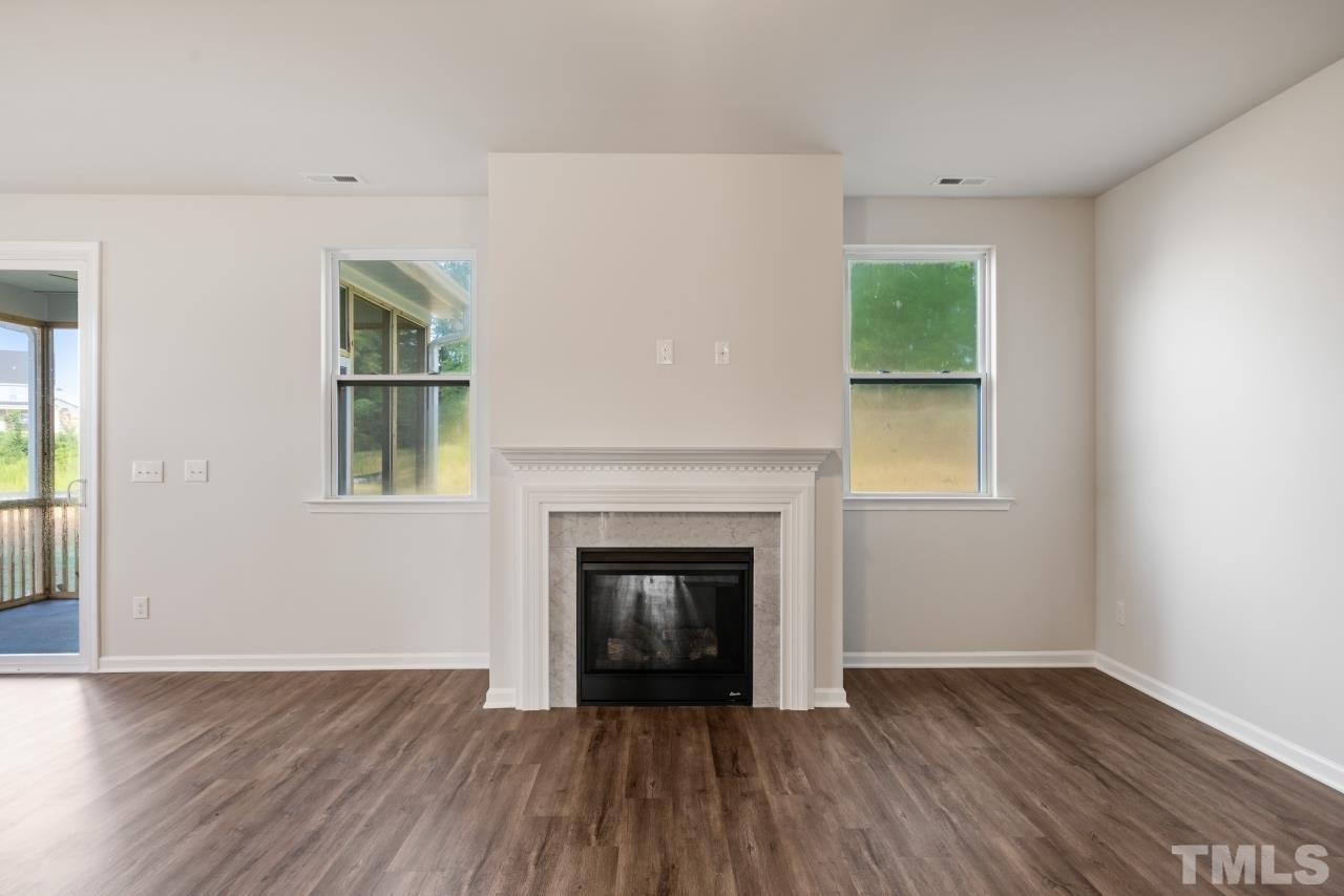 129 Scoville Road Garner, NC 27529 - Photo 10 of 25 an empty room with wooden floor fireplace and windows